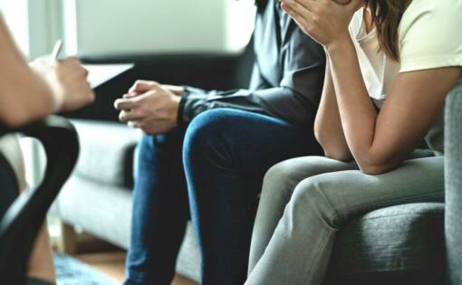 A young distraught couple in therapy sitting on a sofa