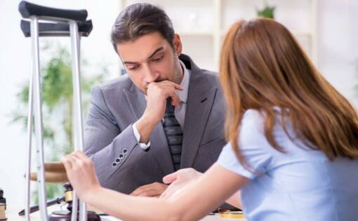 Person holding crutches speaking to a someone in a suit looking at documents